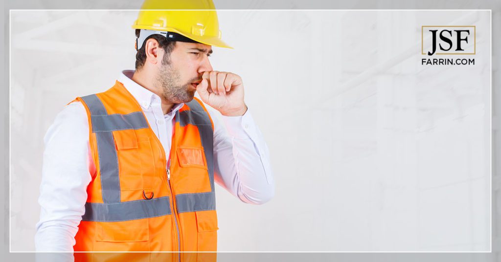 Industrial worker covering his face while coughing.