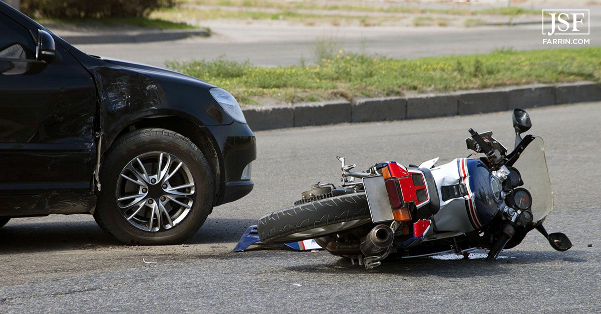Motorcycle on the ground involved in a car collision.