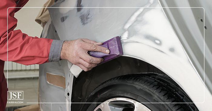 Close up of a person sanding a car for painting during collision repair.