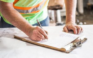 A worker checking off a list on a clipboard.