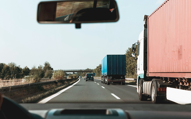 View from a car windshield of large trucks on a highway.