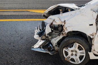 Severely damaged front end of a white car after an accident.