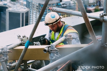 A construction worker in a hi-vis vest and hard hat on a construction site.