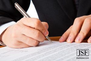 Attorney signing paperwork with a silver pen.