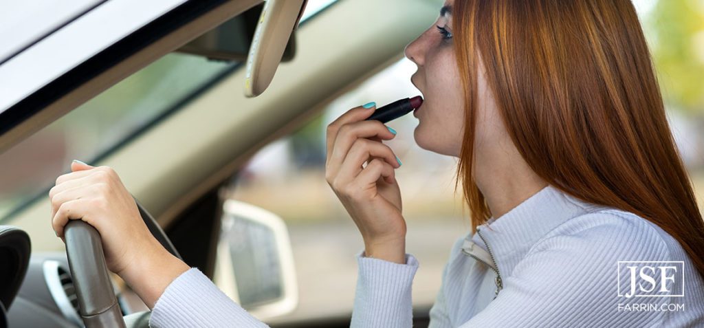 Close up of a young redhead woman driver correcting her makeup