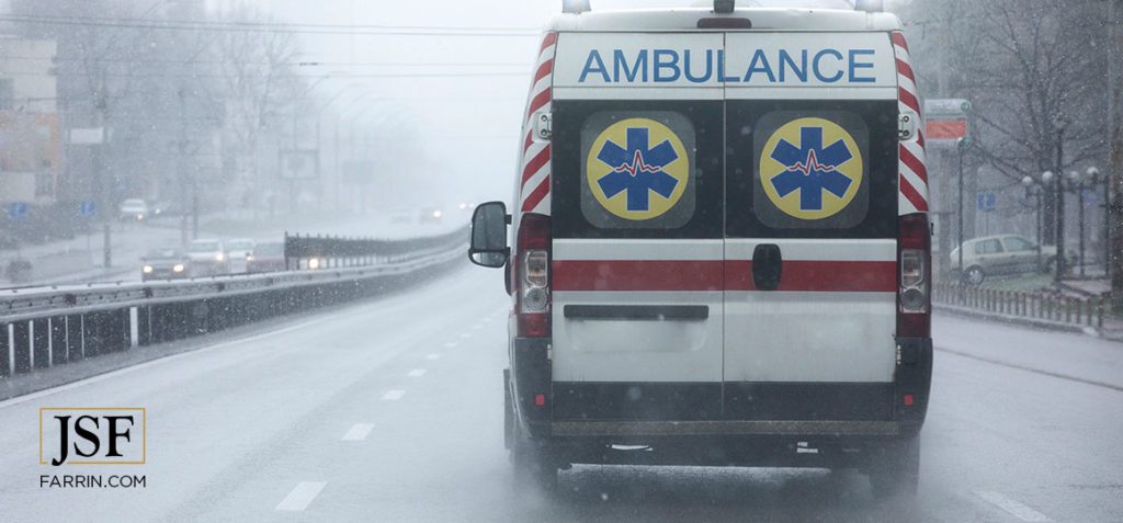 Ambulance moving down the street at high speed under the rain