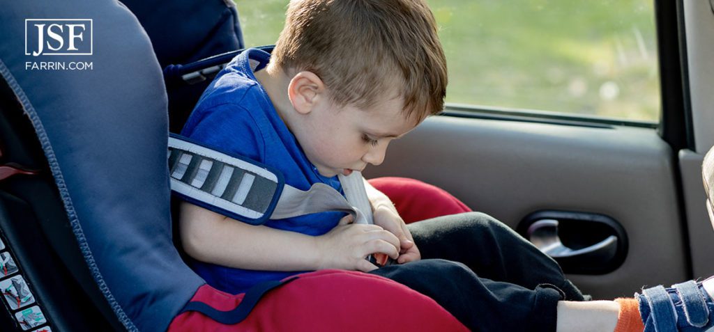 Little boy buckled up with seatbelt inside the car