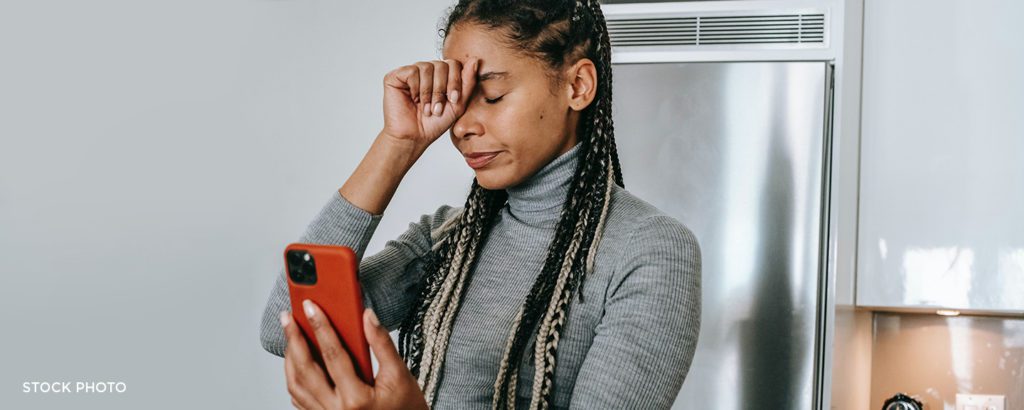 Woman holding her hand to her face, dealing with a difficult phone call.