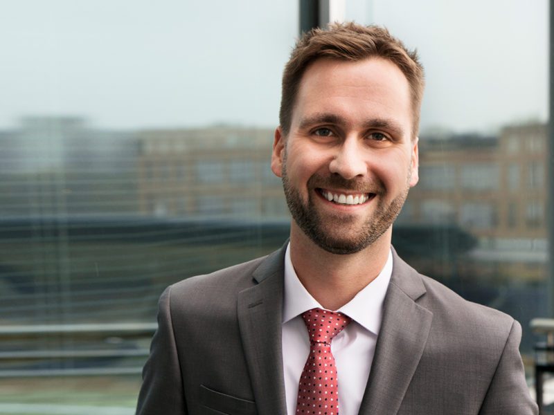 Attorney Ryan Bliss in the Law Offices of James Scott Farrin office in Durham in front of a window