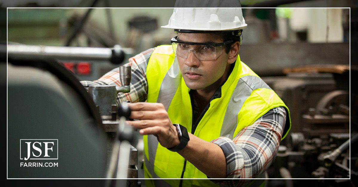 Industrial worker operating machine while wearing goggles to avoid potential eye injuries.
