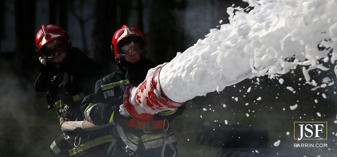Firefighter using chemical foam fire extinguisher to fight the fire flames from an oil tanker truck