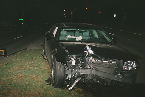 Wrecked black car after a dwi accident at night.