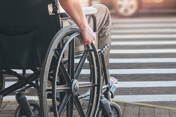 Person in a wheelchair preparing to cross the road at the crosswalk.