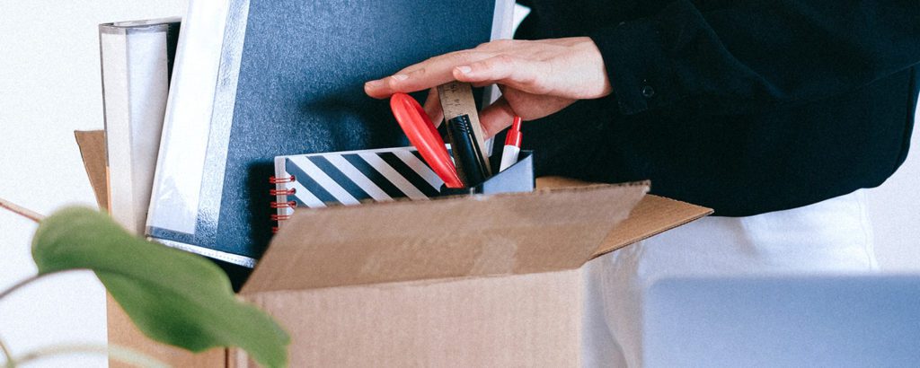 Woman packing a box full of office supplies after being fired.