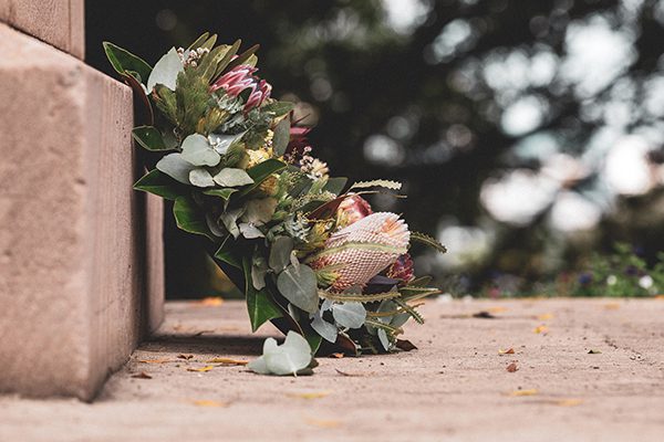 A funeral wreath of flowers leaning on a stone grave in a cemetery.