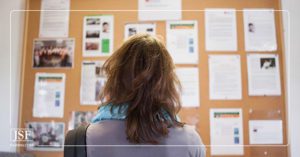 Female employee looking at a large cork bulletin board at work.