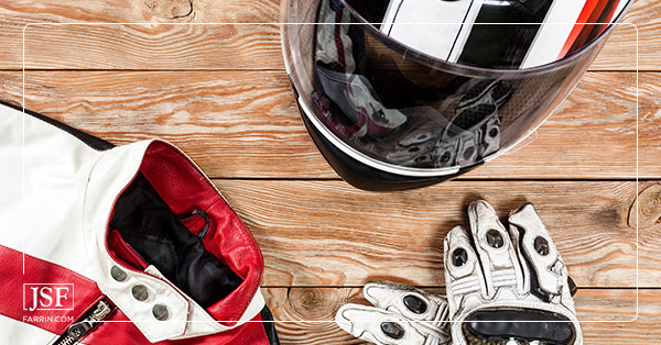 Red, black, & white motorcycle helmet, gloves, and leather jacket are lain out on a wooden surface.