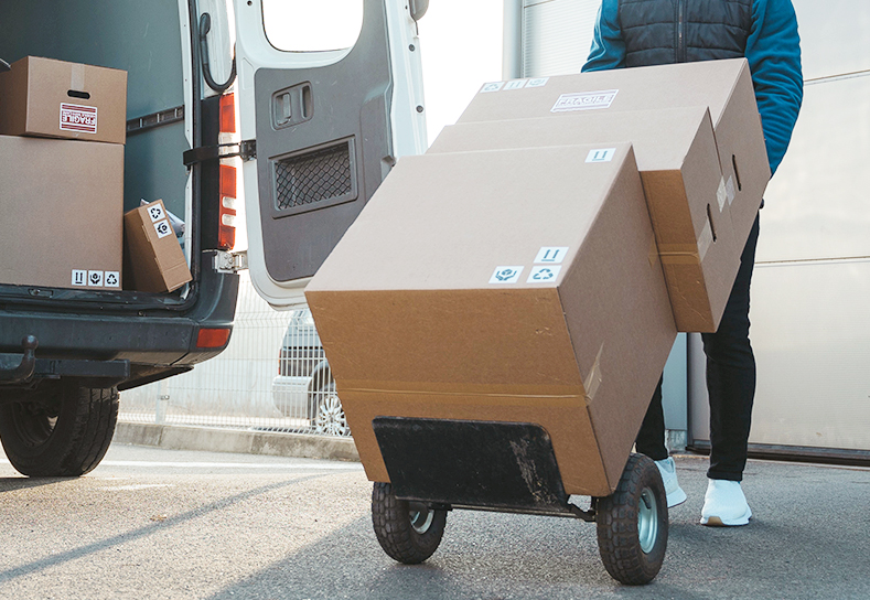 Delivery man with large cardboard boxes on dolly.