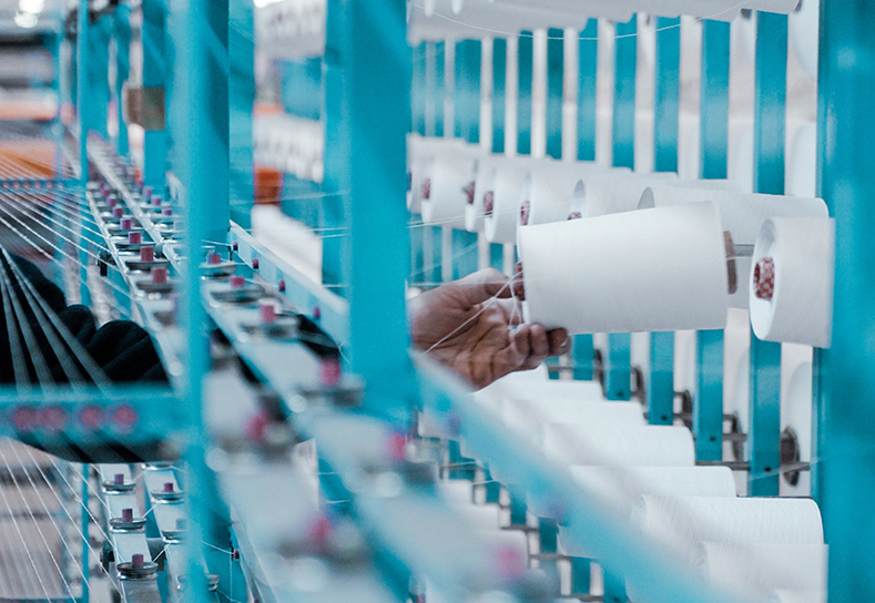 Textile factory worker reaching for a thread cone.