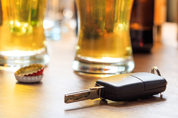 Car key, bottle caps & pints of beer on a counter.