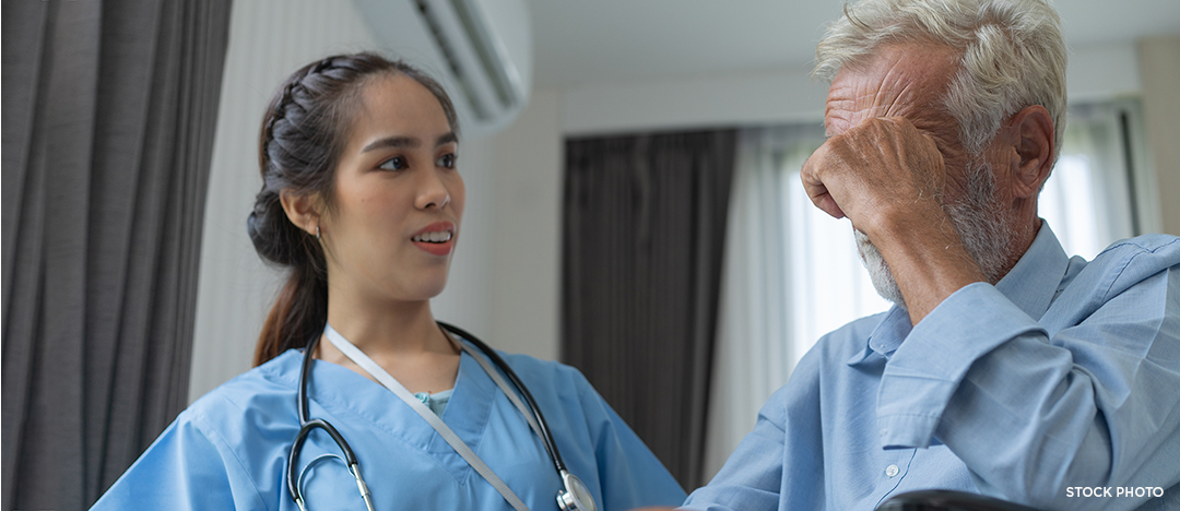 Upset older man holding his head in his hands with a concerned doctor.