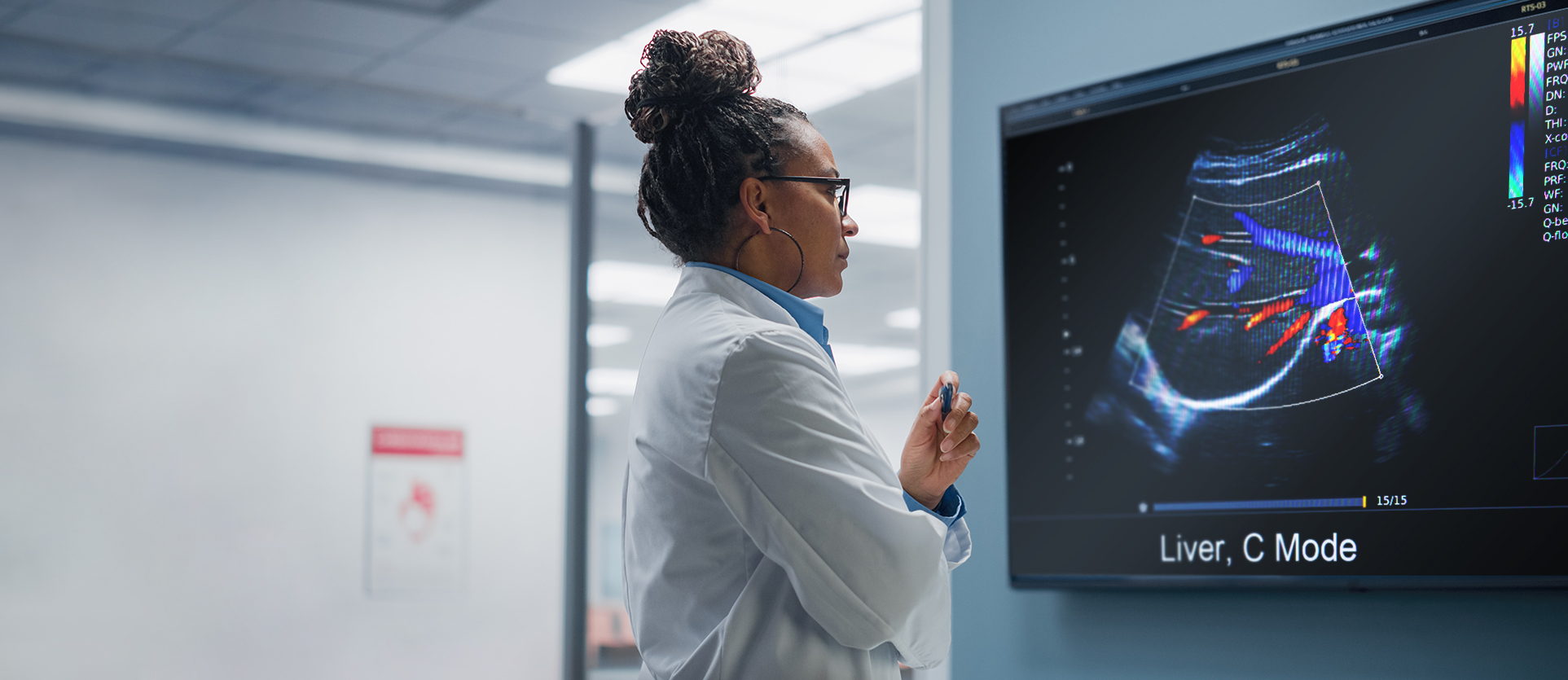 A worried doctor looking at a liver scan result on a large screen in a hospital.