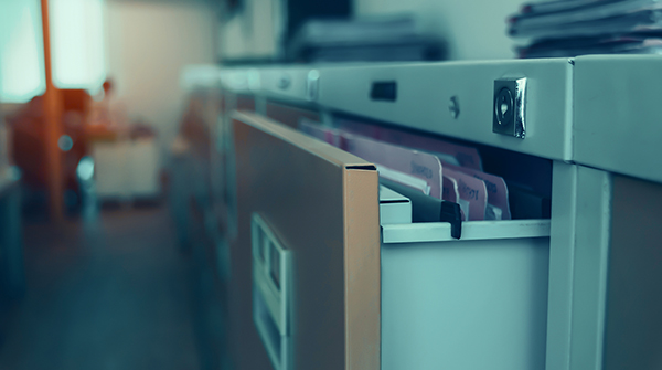 Open filing cabinet of medical records in the dark room of a hospital.