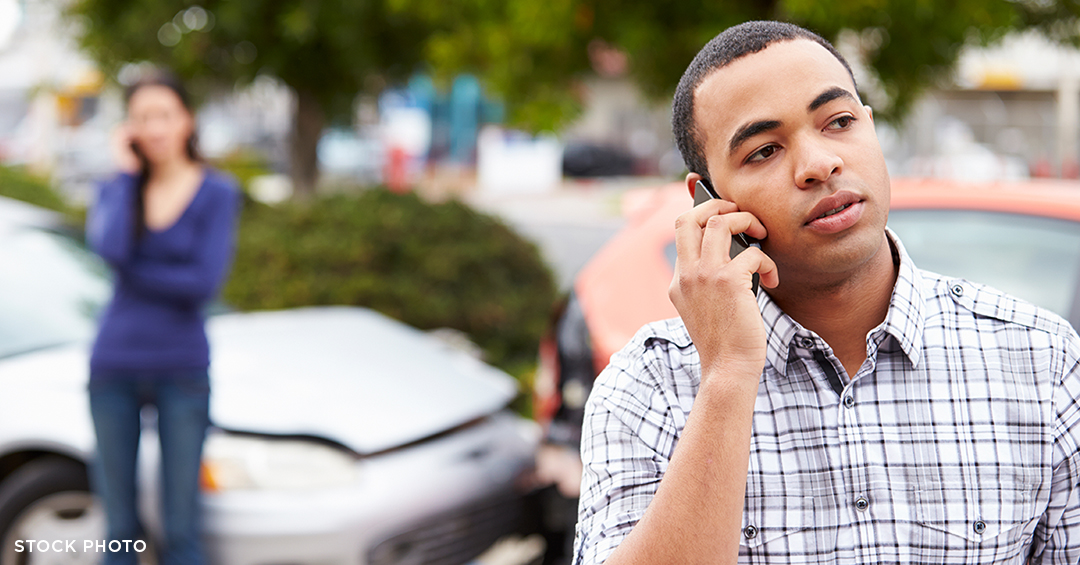 A Black man making a phone call after a car crash.