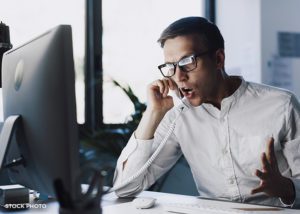 Angry and frustrated man yelling on the phone and gesturing.