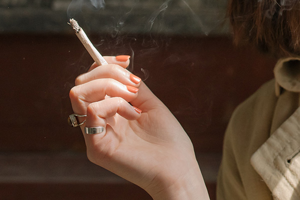 A young woman holding a marijuana blunt in her hand.