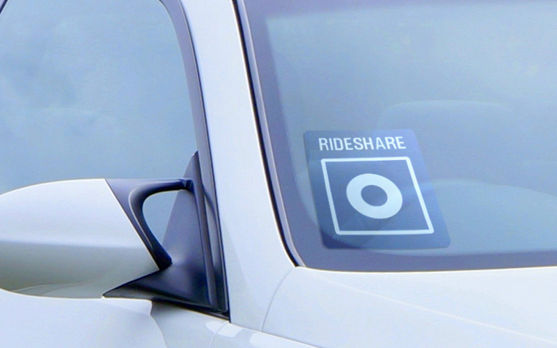 A Ride Share Company logo decal in the windshield of a white car.