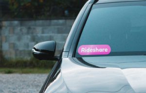 Pink ride share company decal in the windshield of a car.