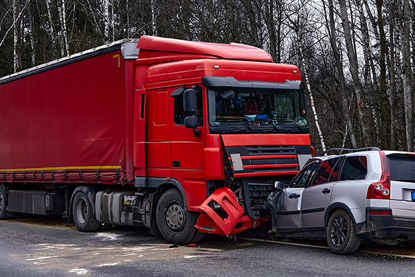 A grey SUV crushed by a large red semi-truck on a highway.
