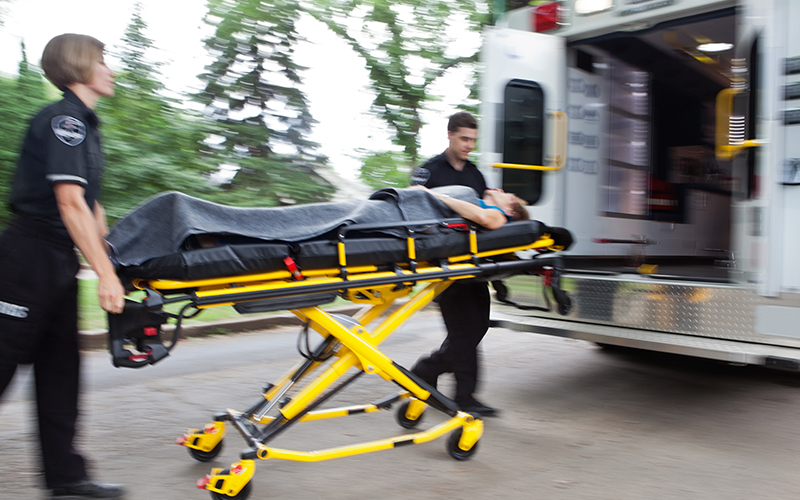 Paramedics loading a crash victim on a stretcher into the back of an ambulance.