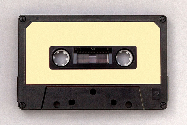A black audio cassette tape with a yellow label.