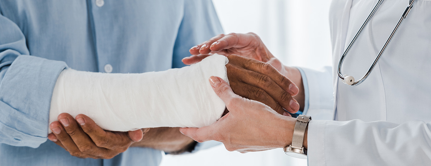 A doctor holding the bandaged arm of an injured worker.