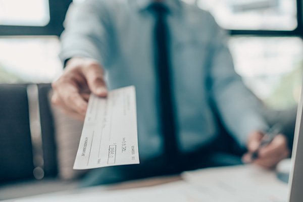 A lawyer handing their client a settlement check at disbursal.