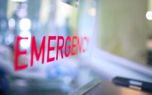 Blurred view of a red EMERGENCY sign at a hospital.