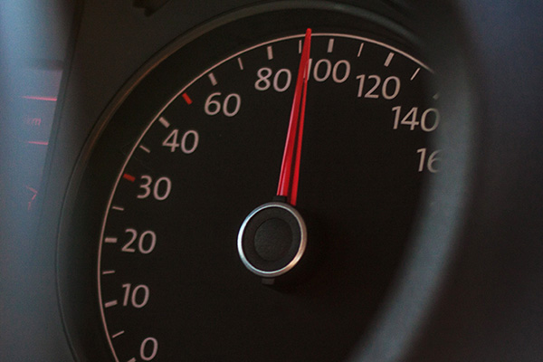 Close up of a car speedometer going dangerously fast.