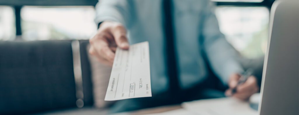 A lawyer handing their client a settlement check at disbursal.