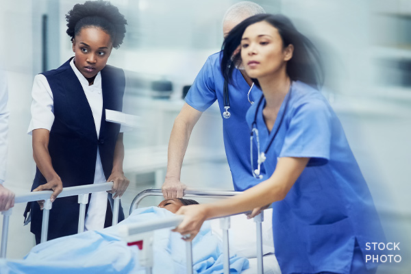 Nurses rushing to push a patient to the emergency room in a heavy stretcher.