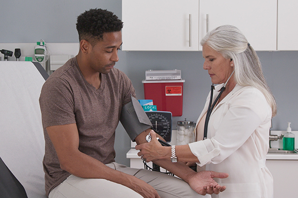 A doctor taking a patient's blood pressure in a medical office during a check up.