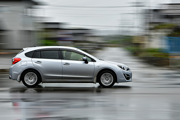 Silver car driving fast on a wet road after the rain.