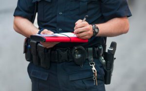 A police officer filling out a form on a notepad while standing.