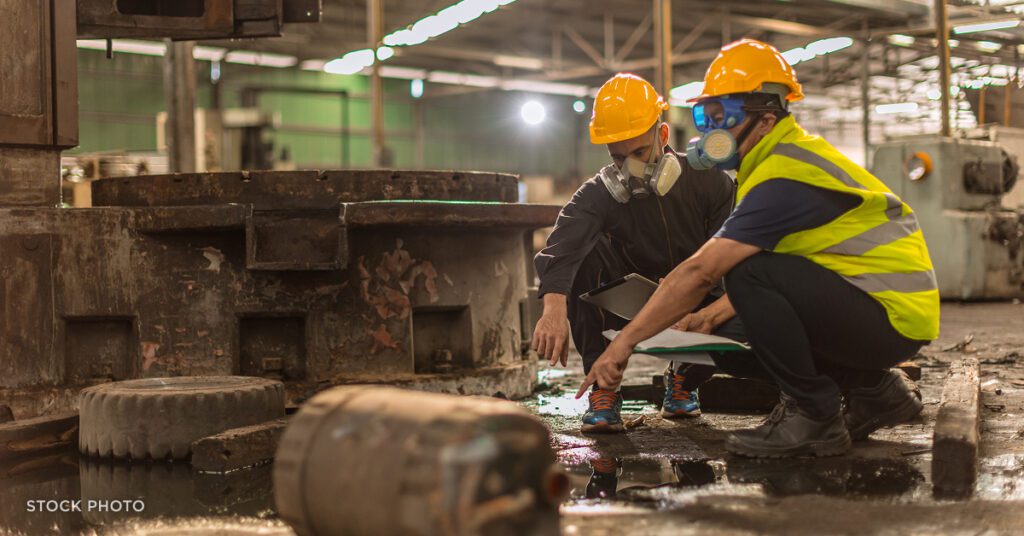 Law Offices of James Scott Farrin North Carolina workers’ compensation attorneys. Manufacturing workers wearing protective gear inspect hazardous spill on factory floor.
