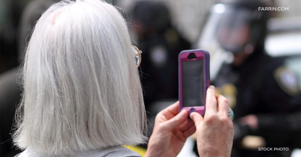 Gray-haired female films police with her phone's camera